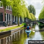 Home 15 네덜란드에서 즐길 수 있는 워터스포츠 - A serene scene of a person paddle surfing on a calm Dutch canal near Amsterdam, surrounded by lush g...
